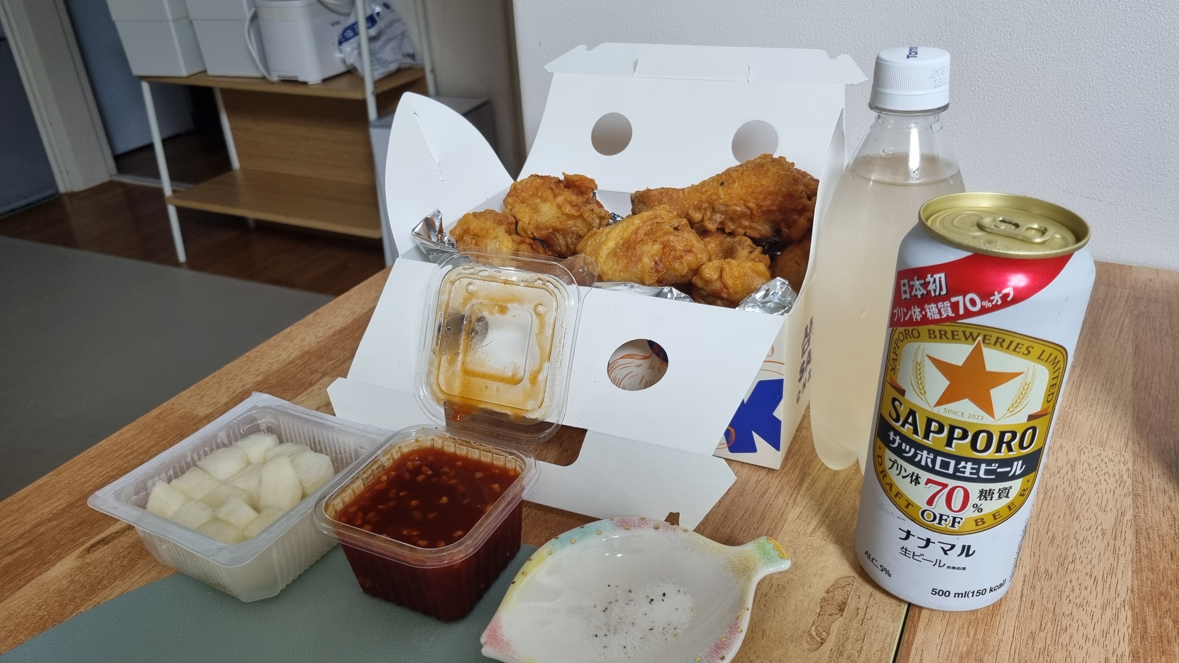 후라이드 치킨과 피클무, 소스, 사포로 맥주와 탄산수가 차려진 식탁