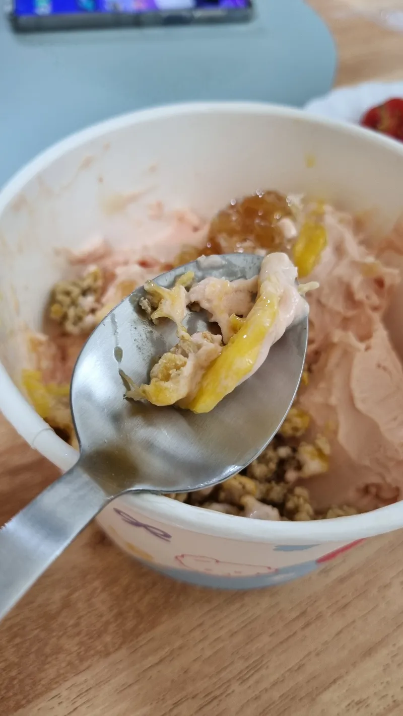 망고 조각과 토핑이 얹어진 요거트 아이스크림 한 숟가락