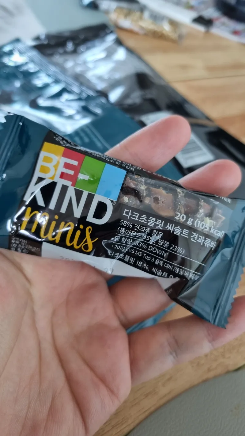 손바닥 위에 올려둔 비카인드 다크초콜릿 씨솔트 견과류바 미니 개별 포장