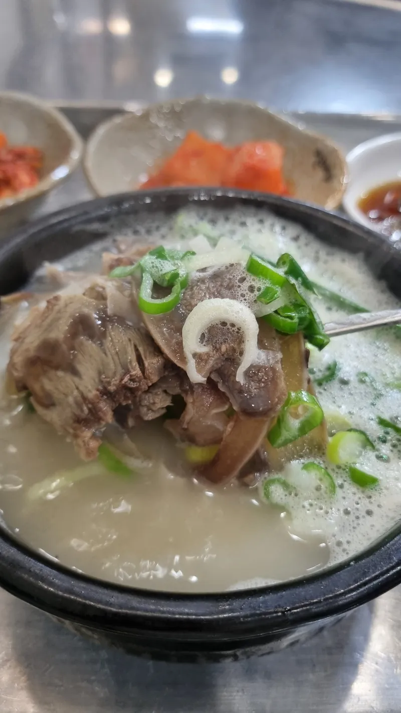 숟가락으로 뜰어 올린 소머리고기와 대파가 담긴 뚝배기